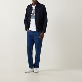 Model wearing Paul Smith Graphic Logo T-Shirt in white with navy overshirt, blue jeans and white trainers.