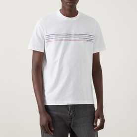 Model wearing Paul Smith Stripe Logo T-Shirt in white with multicolour chest stripe graphic, crew neck and short sleeves, styled with dark grey jeans.
