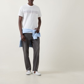 Model wearing Paul Smith Stripe Logo T-Shirt in white with grey trousers and white trainers, light blue shirt tied at waist.