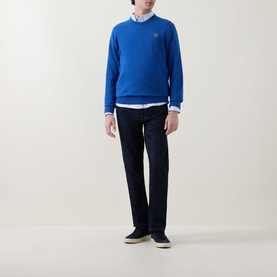 Model wearing Paul Smith Zebra Badge Logo Sweater in blue crew neck, styled with white shirt and dark navy trousers.