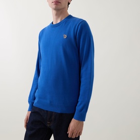 Model wearing Paul Smith Zebra Badge Logo Sweater in blue, crew neck cotton knitwear with ribbed trims, styled with dark jeans.