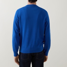 Model wearing Paul Smith Zebra Badge Logo Sweater in blue, back view, crew neck cotton knit with ribbed trims, styled with dark jeans.