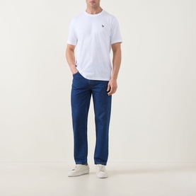 Model wearing Paul Smith white crew neck T-shirt with small chest logo, styled with navy trousers and white trainers.