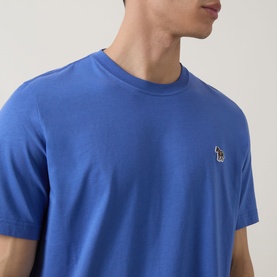 Model wearing Paul Smith Zebra Badge T-Shirt in blue, crew neck, short sleeves, with small zebra logo badge on chest.