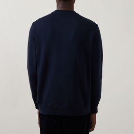 Model wearing Paul Smith blue crew neck sweatshirt, back view, styled with dark trousers.