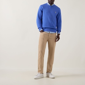 Model wearing Paul Smith Blue Zebra Logo Sweatshirt with beige chinos, white shirt, and white trainers.