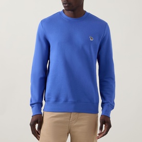 Model wearing Paul Smith Zebra Logo Sweatshirt in blue, crew neck with chest logo detail, styled with beige trousers.