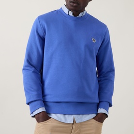 Model wearing Paul Smith Zebra Logo Blue Crew Neck Sweatshirt, styled with a light blue shirt and beige chinos.
