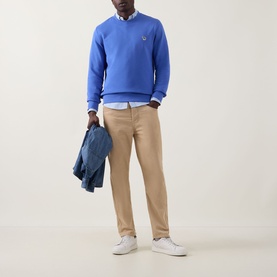 Model wearing Paul Smith Blue Zebra Logo Crew Neck Sweatshirt, styled with beige chinos, white shirt and white trainers, carrying a denim jacket.