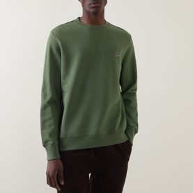 Model wearing Paul Smith Zebra Logo Sweatshirt in green, crew neck with ribbed trims and zebra badge, styled with dark trousers.