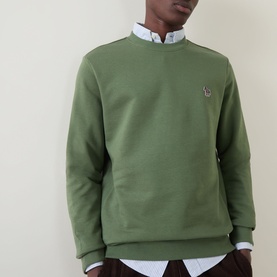 Model wearing Paul Smith Zebra Logo Sweatshirt in green with crew neck and zebra badge, styled over a light blue shirt.