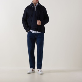 Model wearing Paul Smith Zebra Logo Half-Zip Sweatshirt in blue, styled with navy jacket, dark jeans and white trainers.