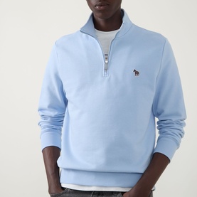 Model wearing Paul Smith Zebra Logo Half-Zip Sweatshirt in blue, with funnel neck, embroidered zebra patch, over white crew neck top