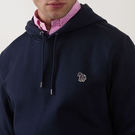 Model wearing Paul Smith Zebra Logo Hoodie in blue with small zebra chest logo, styled with a pink gingham shirt underneath.