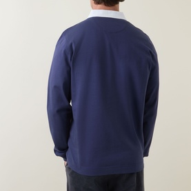 Model wearing Paul Smith blue cotton polo, back view, styled with white collar visible at neckline and dark trousers.
