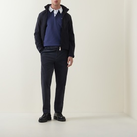 Model wearing Paul Smith blue cotton polo, styled with navy zip-up jacket, navy trousers, and black chunky shoes.