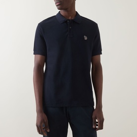 Model wearing Paul Smith Zebra Polo Shirt in blue piqu&eacute; cotton with zebra logo badge at chest, paired with navy trousers
