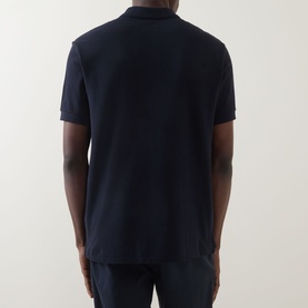 Model wearing Paul Smith Zebra Polo Shirt in blue, rear view, short sleeves, straight hemline, piqu&eacute; fabric, paired with navy trousers