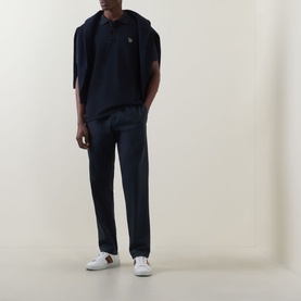 Model wearing Paul Smith Blue Zebra Polo Shirt with navy chinos and a navy hoodie tied over shoulders, styled with white trainers.