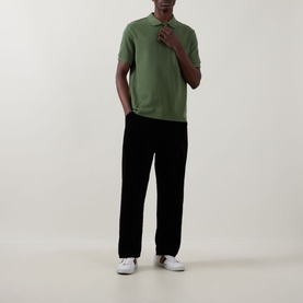 Model wearing Paul Smith green cotton polo shirt, styled with black trousers and white trainers.