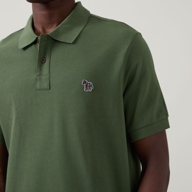 Model wearing Paul Smith green cotton polo shirt with signature zebra logo badge, short sleeves and three-button placket