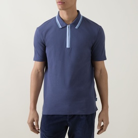 Model wearing Paul Smith blue cotton polo shirt with contrast light blue tipped collar and zip placket, styled with dark blue jeans.