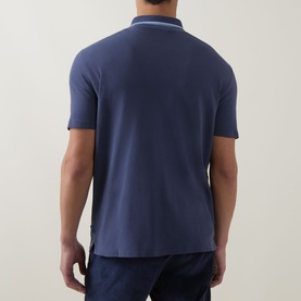 Model wearing Paul Smith blue cotton polo shirt, back view, with light blue tipped collar detail and navy trousers.