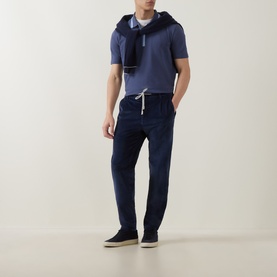 Model wearing Paul Smith blue cotton polo with navy joggers and dark trainers, white drawstring detail visible.