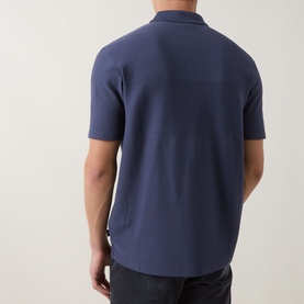 Model wearing Paul Smith blue cotton polo shirt, rear view, styled with dark jeans