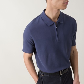 Model wearing Paul Smith blue cotton zip-neck polo shirt, paired with dark navy trousers and a leather belt.