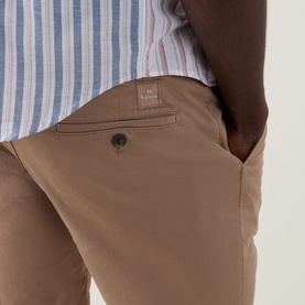 Model wearing Paul Smith Regular Fit Twill Chino Shorts in brown, with button fastening and branded patch detail, styled with a striped shirt.