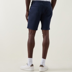 Model wearing Paul Smith Regular Fit Twill Chino Shorts in blue, rear view, styled with white trainers and white socks.