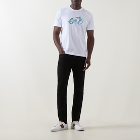 Model wearing Paul Smith Logo Tapered Jeans in blue, slim tapered fit, styled with white graphic T-shirt and white trainers.