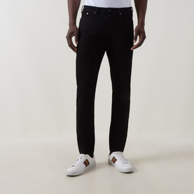 Model wearing Paul Smith Logo Tapered Jeans in blue, slim tapered cut with five-pocket style, styled with white leather trainers.