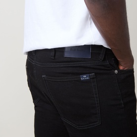 Model wearing Paul Smith Logo Tapered Jeans in blue, close-up of back pocket with logo patch detail, slim tapered fit.