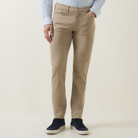 Model wearing Paul Smith Slim Tapered Jeans in brown, styled with a light blue shirt and navy suede loafers.