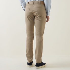Model wearing Paul Smith Slim Tapered Jeans in brown, rear view, styled with a light blue shirt and navy suede loafers.