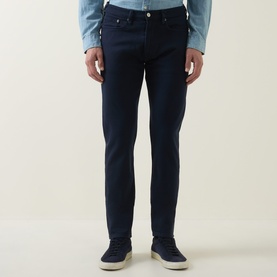 Model wearing Paul Smith Blue Slim Jeans in dark navy, paired with a light blue shirt and white trainers.