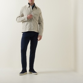 Model wearing Paul Smith Blue Slim Jeans, styled with a stone overshirt and navy suede shoes.