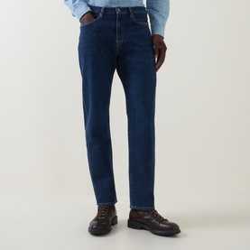 Model wearing Paul Smith blue straight-leg jeans in dark wash denim, styled with a light blue shirt and brown leather boots.
