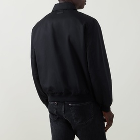 Model wearing Calvin Klein black casual jacket, rear view, styled with dark wash jeans. Clean bomber silhouette with ribbed hem and collar.