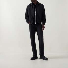 Model wearing Calvin Klein black casual jacket with zip fastening, styled with dark jeans and black leather shoes.