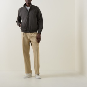 Model wearing Calvin Klein Beluga cotton casual jacket with zip front, styled with beige chinos and white trainers.