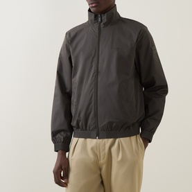 Model wearing Calvin Klein Casual Jacket in Beluga, dark grey zip-up with funnel neck and elasticated cuffs, styled with beige trousers