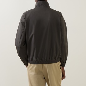 Model wearing Calvin Klein casual jacket in Beluga, rear view, with elasticated hem and cuffs, styled with beige trousers
