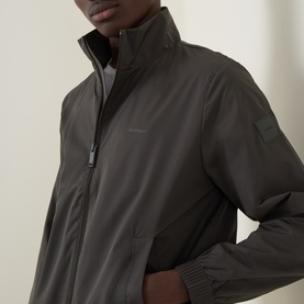 Model wearing Calvin Klein Beluga casual jacket with high funnel neck, zip fastening, and sleeve pocket detail.