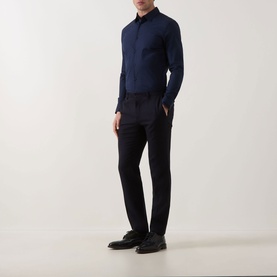 Model wearing Calvin Klein Slid Stretch Shirt in Dark Sapphire, paired with navy tailored trousers and black leather shoes.