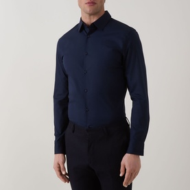 Model wearing Calvin Klein Slid Stretch Shirt in Dark Sapphire, point collar, long sleeves, front button fastening, paired with navy trousers