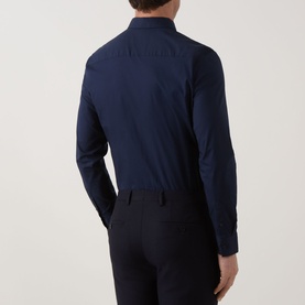 Model wearing Calvin Klein Slid Stretch Shirt in Dark Sapphire, rear view showing long sleeves and buttoned cuffs, styled with navy trousers