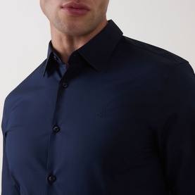 Model wearing Calvin Klein Slid Stretch Shirt in Dark Sapphire, showing point collar, front button fastening and tonal logo embroidery.